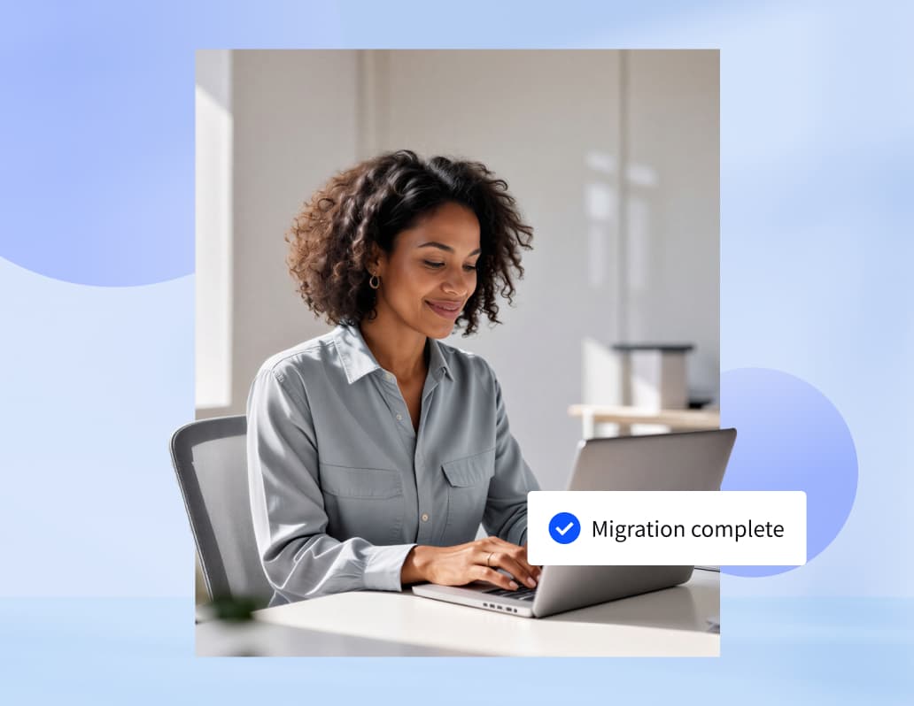 Woman at computer smiling with Migration Completed checked of on an overlay